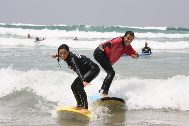 Two surfers riding waves together during a surf camp session in Lanzarote