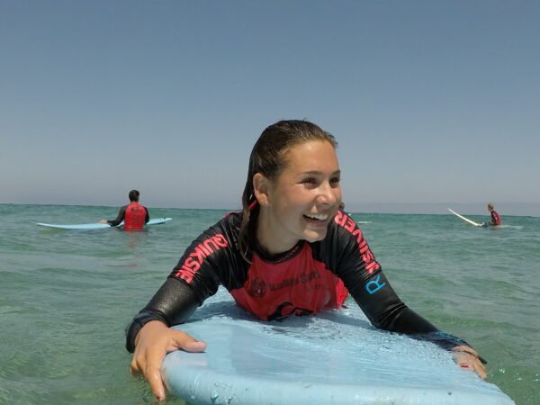 Surf student smiling on a surfboard in the ocean during a lesson in Playa Blanca, Lanzarote