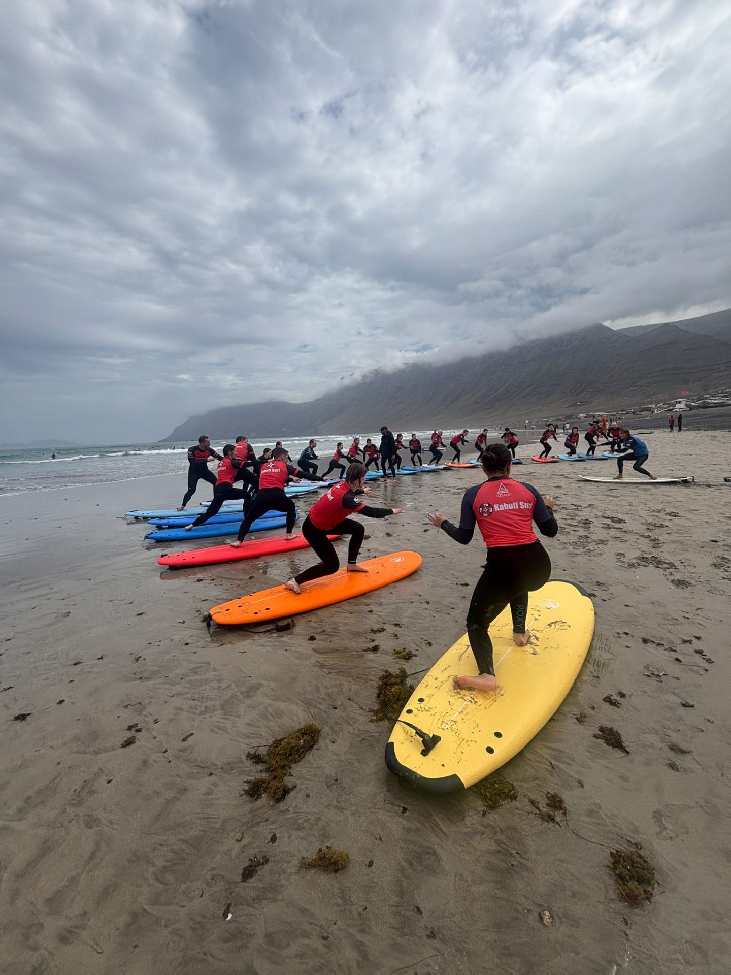 Group of Kaboti Surf students practising the pop-up on Famara beach, Lanzarote